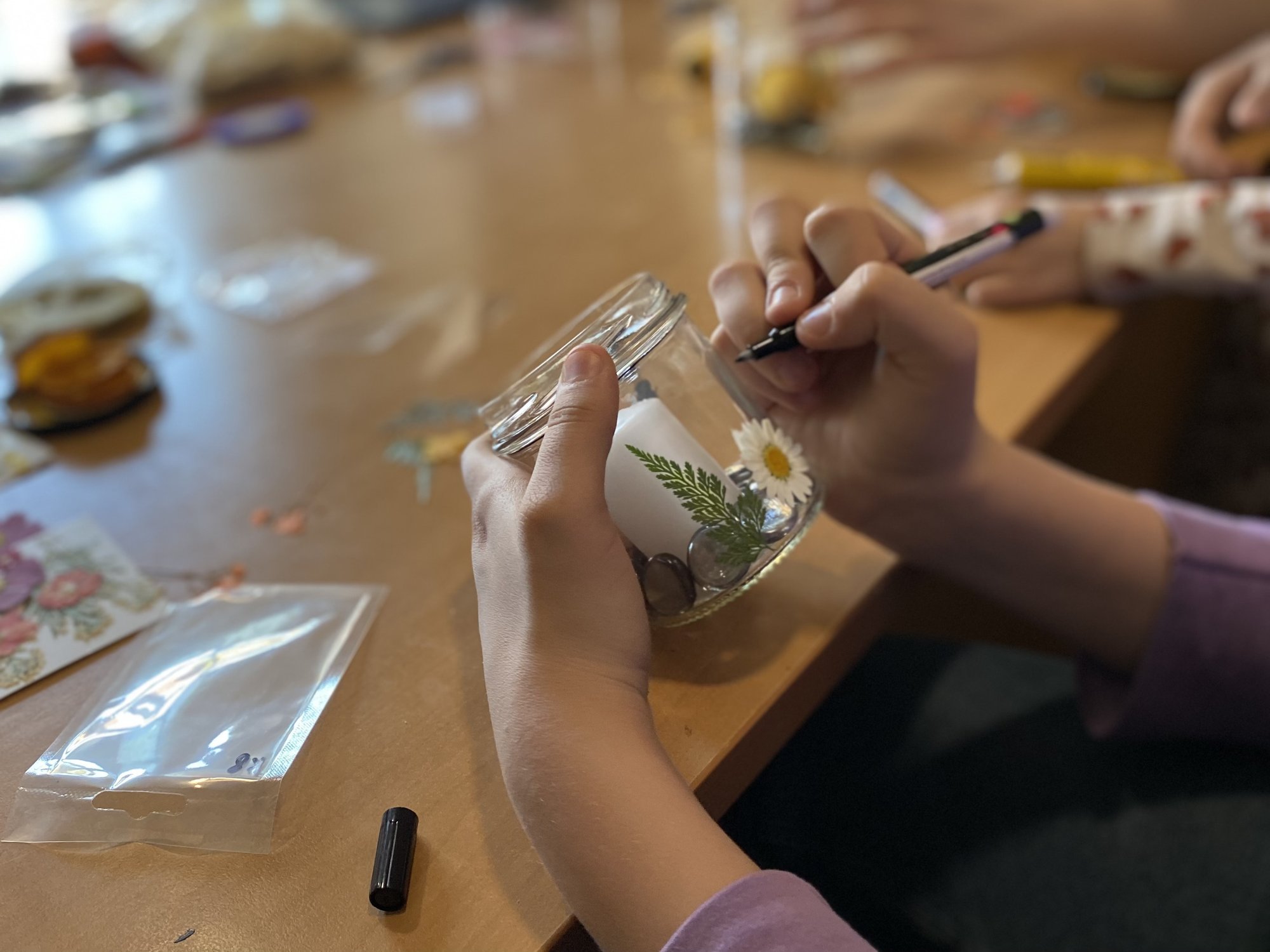 Zbliżenie na dziecięce dłonie ozdabiające szklany świecznik. Zbliżenie na dziecięce dłonie ozdabiające szklany świecznik.