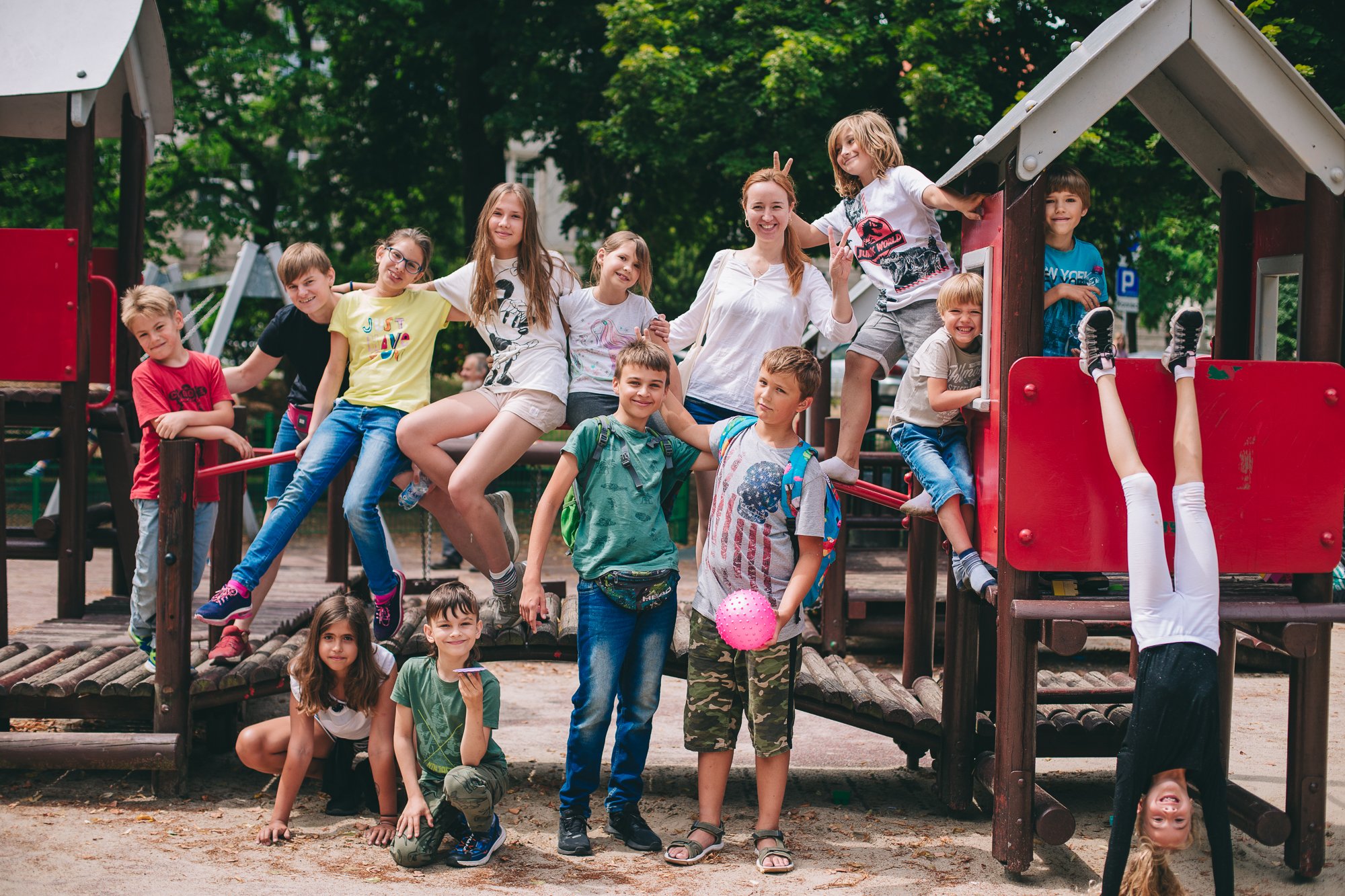 fot. Marta Sobala Grupa dzieci w różnym wieku pozuje do zdjęcia na tle placu zabaw.