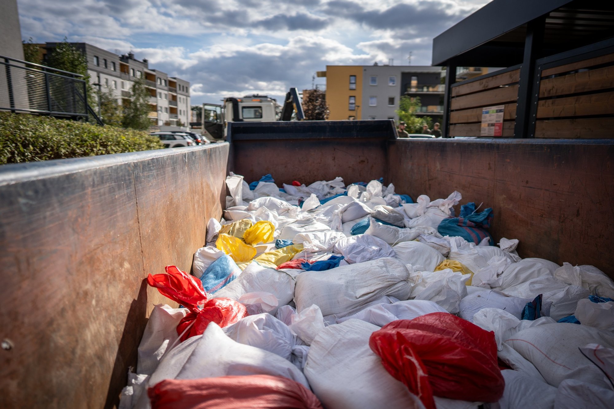 zdjęcie: Ekosystem Kolorowa fotografia przedstawia widok na duży kontener wypełniony workami z piaskiem.